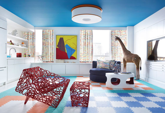 A large playroom designed by Sandra Nunnerley features artwork by Raymond Parker, a red chair and ottoman designed by Cheick Diallo and a table by Jacques Jarrige.