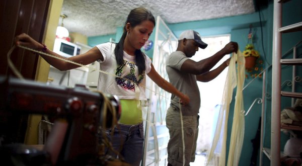 Cuban entrepreneur Barbara Fernandez Franco works in her home in Havana as her boyfriend Michel Perez Casanova helps. (Credit: David Gilkey/NPR)