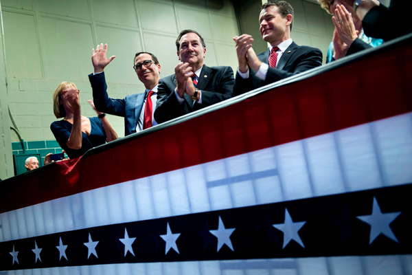 Secretary of the Treasury Steven Mnuchin waving as President Trump speaks about tax reform at the Indiana Farm Bureau building (Credit: Getty Images)