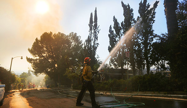 A firefighter puts out a wildfire in Bel Air (Photo by Mario Tama/Getty Images)
