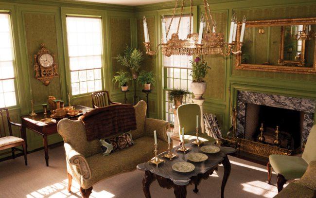 The “green room” at Stewart’s Bedford home features brass accents and an early-19th-century mirror, which reflects an Austrian giltwood chandelier. 