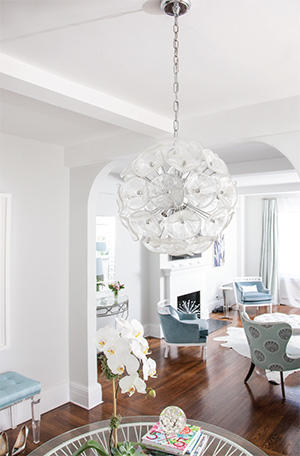 A glass light fixture hangs over a glass table in the apartment’s entryway (Credit: STUDIO SCRIVO)