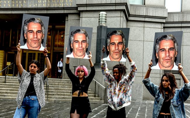 A protest group holds up signs of Jeffrey Epstein (Credit: Getty Images)