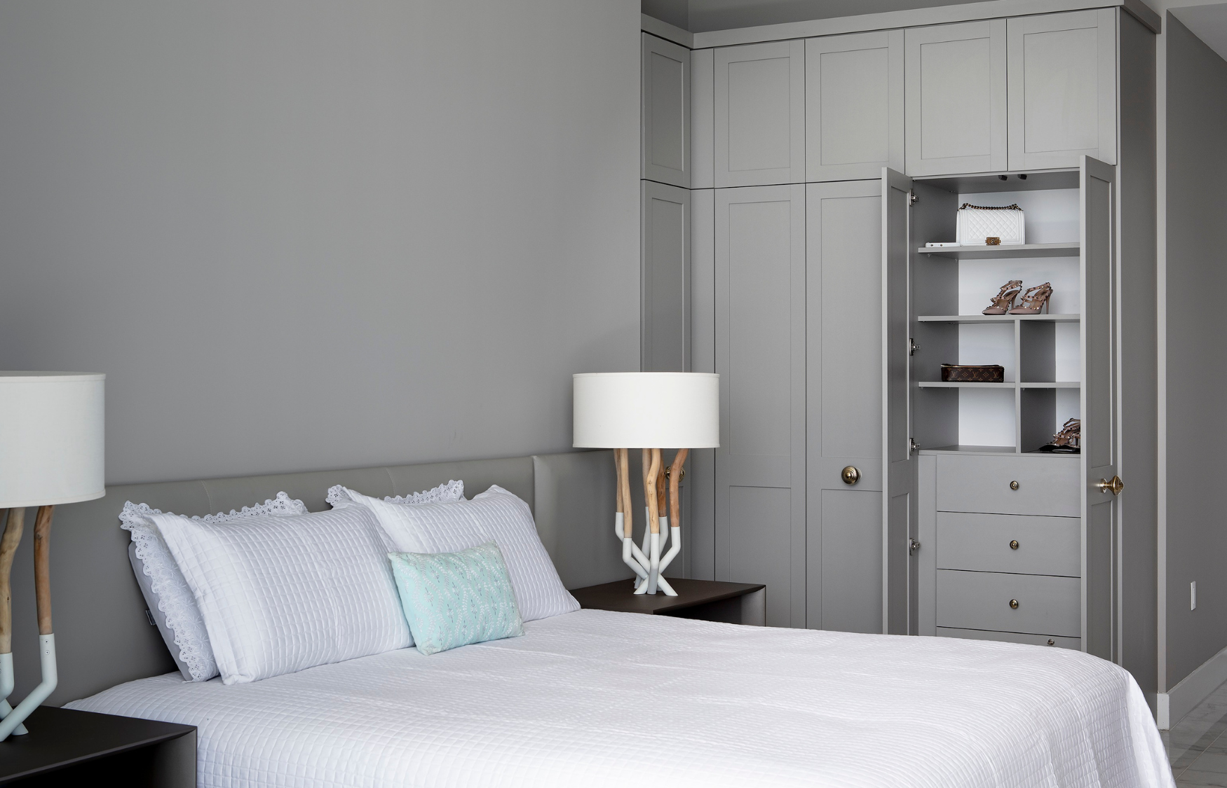 This spare guest room that did not have any closet space was transformed into a functional sleeping area with a custom wardrobe. Using a finish that aesthetically matches the tones of the room, this custom wardrobe holds room for hanging, shelving and sleek drawers behind doors. Photo Creds: Michael Butler